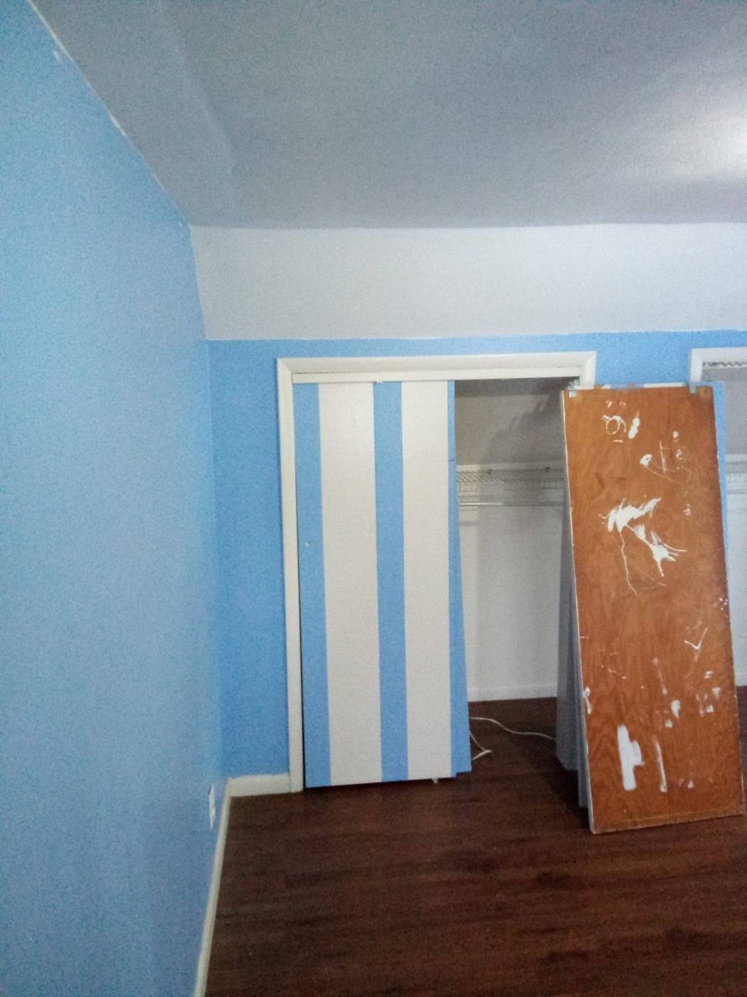 Bedroom before: bright blue walls and a striped closet door